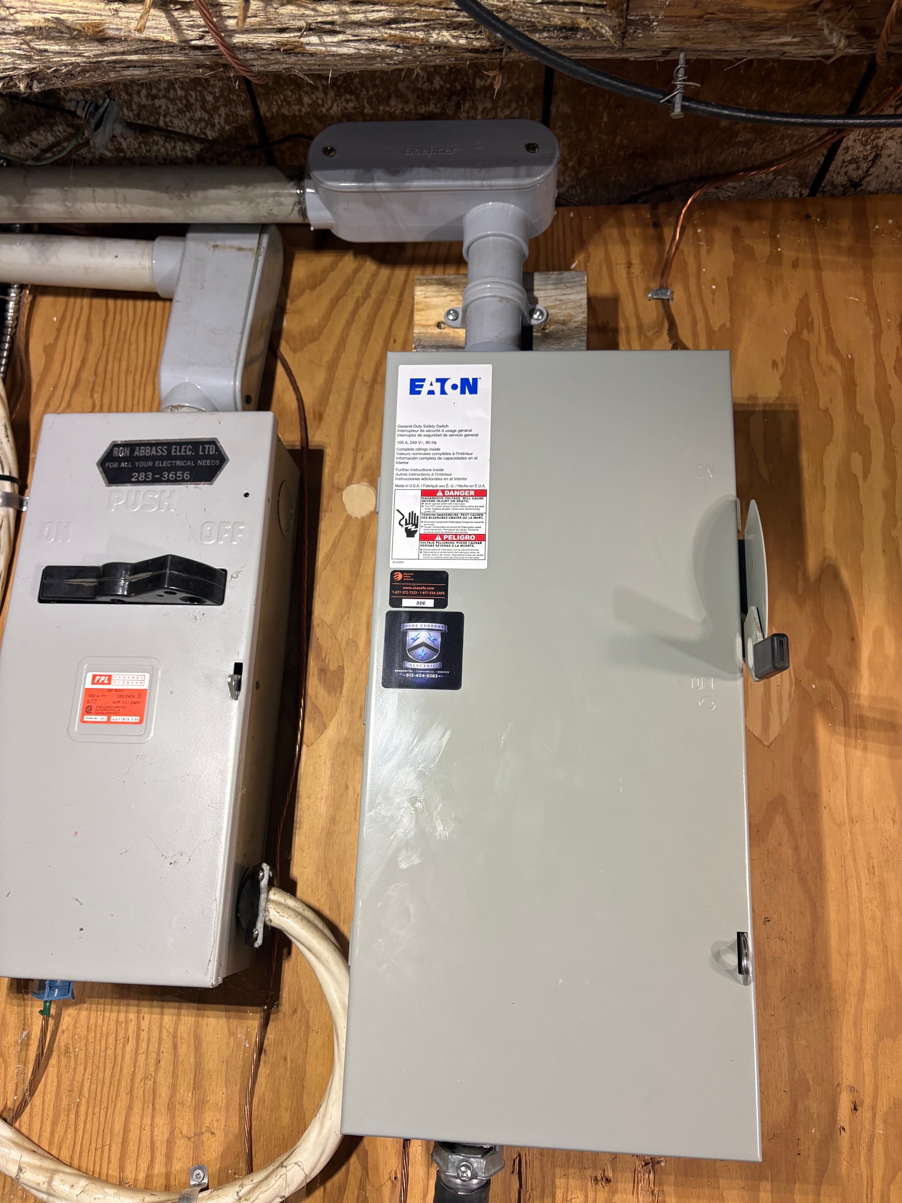 New Eaton electrical panel installed on plywood backing above the existing disconnect enclosure, with service conduit, in a Smiths Falls home rewire