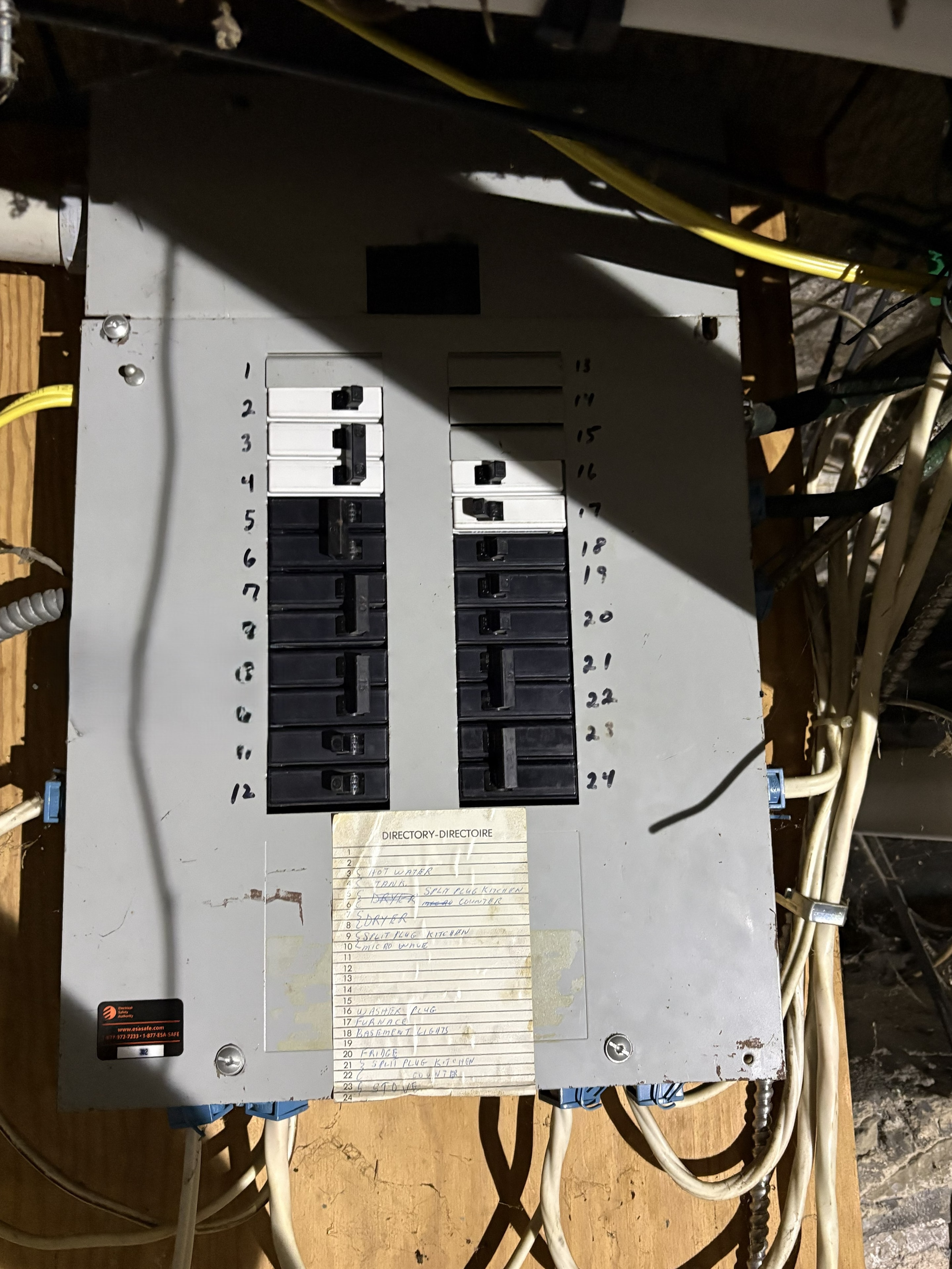 Existing electrical panel with handwritten circuit directory, mounted in an open wall cavity in a Smiths Falls home prior to rewire